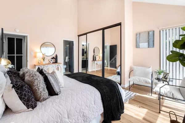 a bedroom with a bed mirror and a large window with outer view
