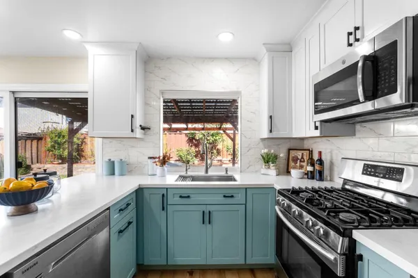 a kitchen with stainless steel appliances a sink a stove a microwave cabinets and a window