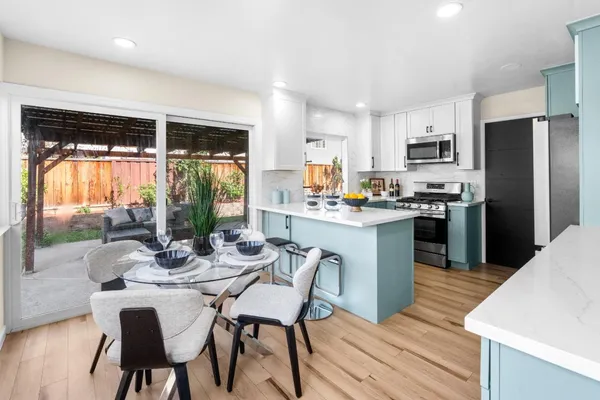 a kitchen with stainless steel appliances granite countertop a table chairs refrigerator and sink
