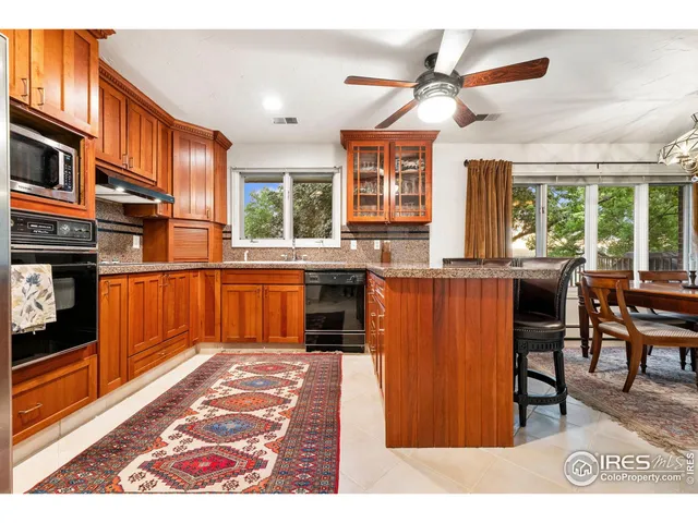 a kitchen with stainless steel appliances granite countertop wooden cabinets a dining table and chairs