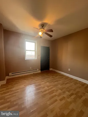 a view of an empty room with window and chandelier fan