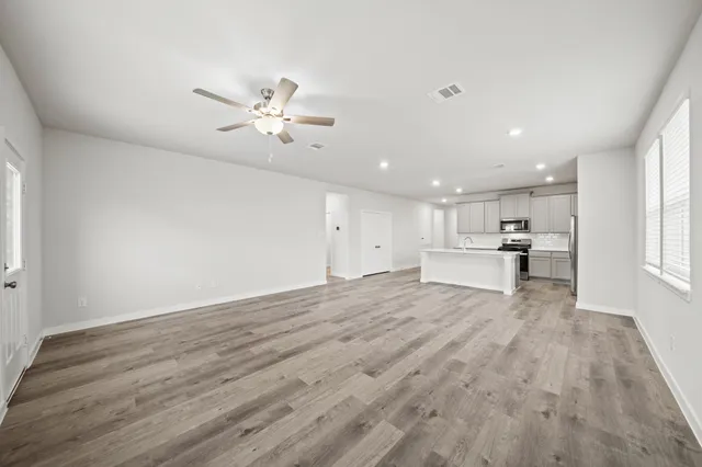 a view of kitchen and empty room with wooden floor and windows