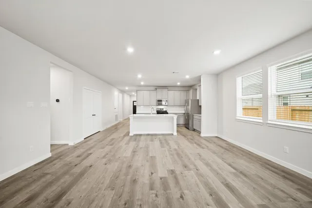 a view of a kitchen with wooden floor electronic appliances and windows