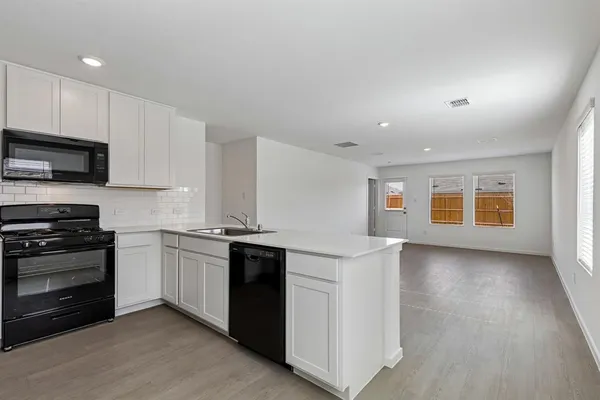 a kitchen with stainless steel appliances granite countertop a stove top oven a sink and a microwave