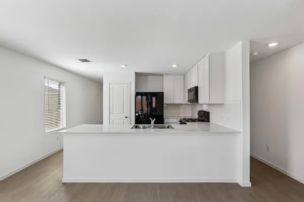 a view of kitchen with kitchen island white cabinets and stainless steel appliances