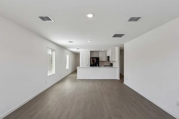 a view of empty room with wooden floor and a window