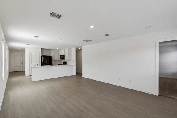 a view of an empty room with kitchen and a window