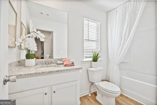 a bathroom with a granite countertop sink toilet and mirror
