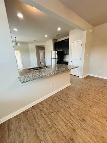 a view of kitchen with kitchen island granite countertop a sink and refrigerator