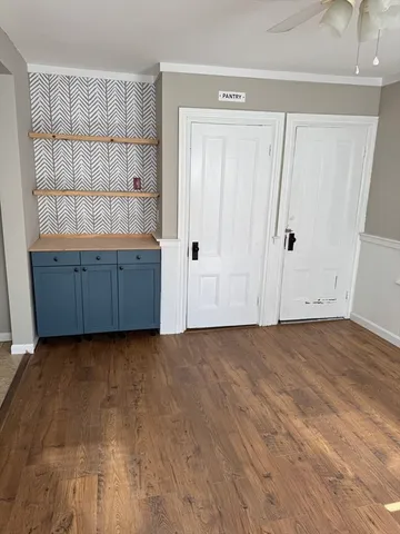 a view of an empty room with wooden floor and cabinet