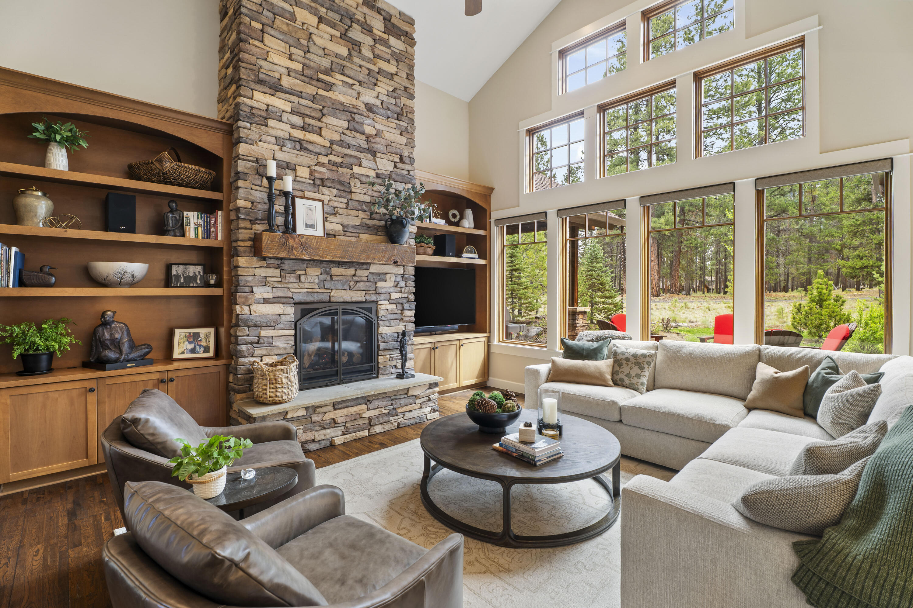 56155 Sable Rock Loop, Unit 277 Bend, OR 97707 - Photo 3 of 63 Soaring ceilings, a dramatic floor-to-ceiling stone fireplace, and expansive windows create a warm and light-filled great room overlooking the natural landscape.