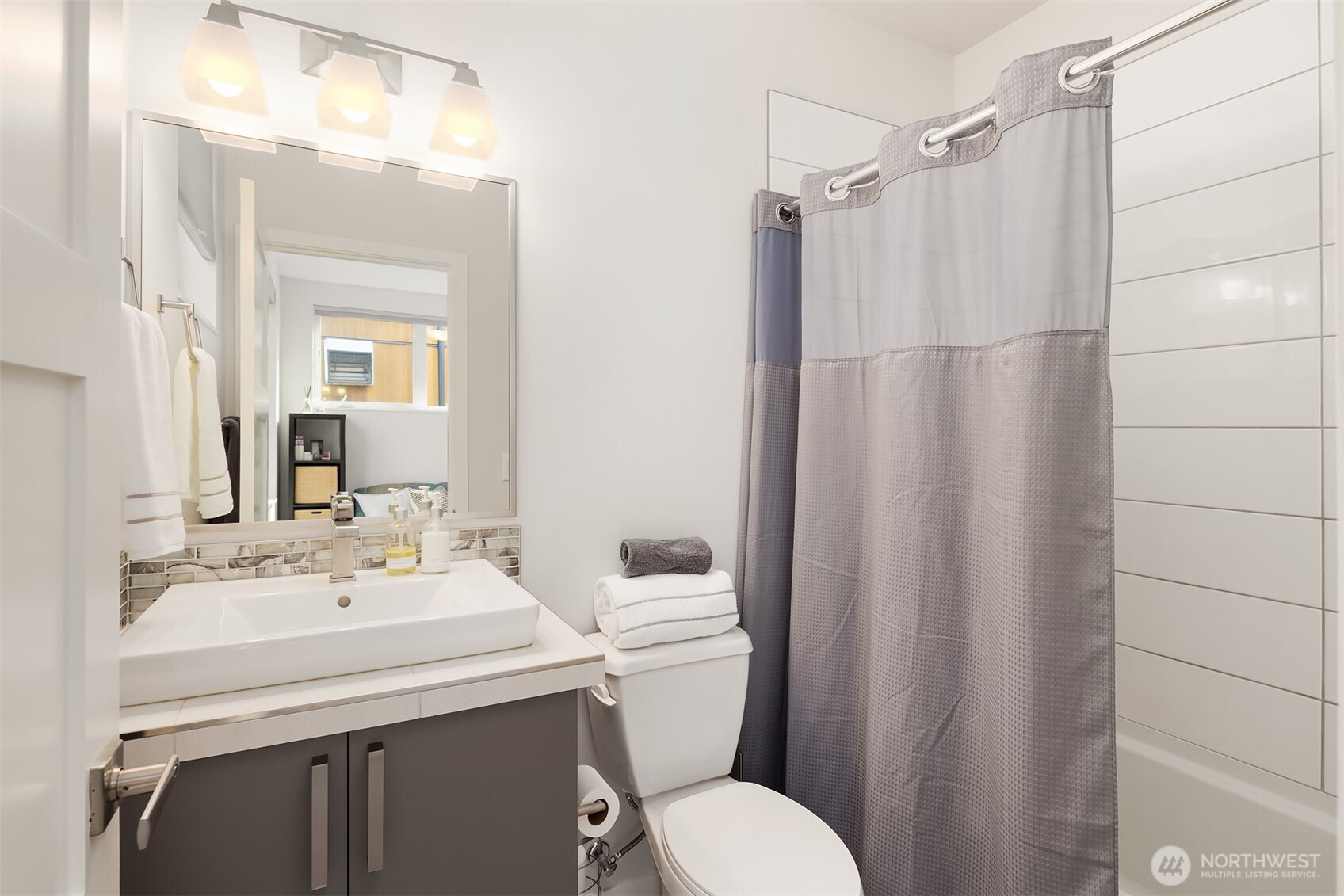 3300 Northeast 65th Street, Unit 211 Seattle, WA 98115 - Photo 12 of 15 a bathroom with a sink a toilet a mirror and shower curtain