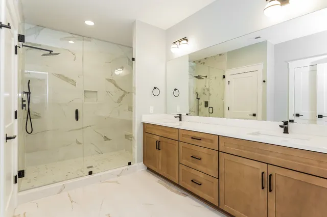 a bathroom with double sink shower and a mirror