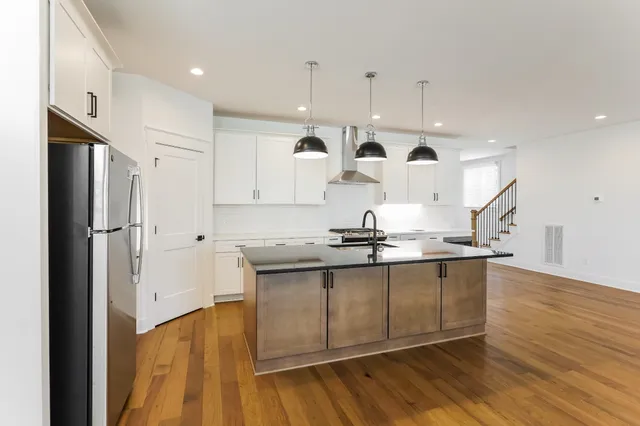 a kitchen with stainless steel appliances granite countertop a sink a stove and a refrigerator