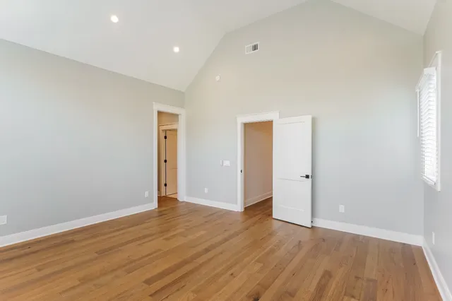 a view of an empty room with wooden floor and closet