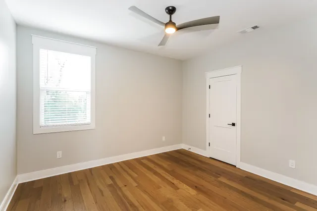 a view of empty room with wooden floor and fan