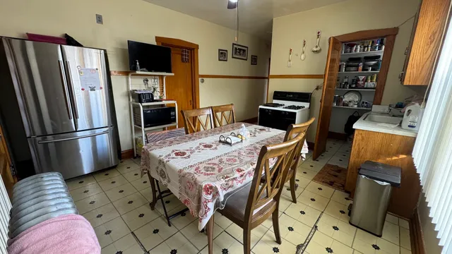 a kitchen with stainless steel appliances kitchen island granite countertop a refrigerator a stove a sink dishwasher and a dining table with wooden floor