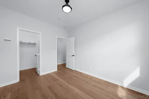 a view of empty room with wooden floor and fan