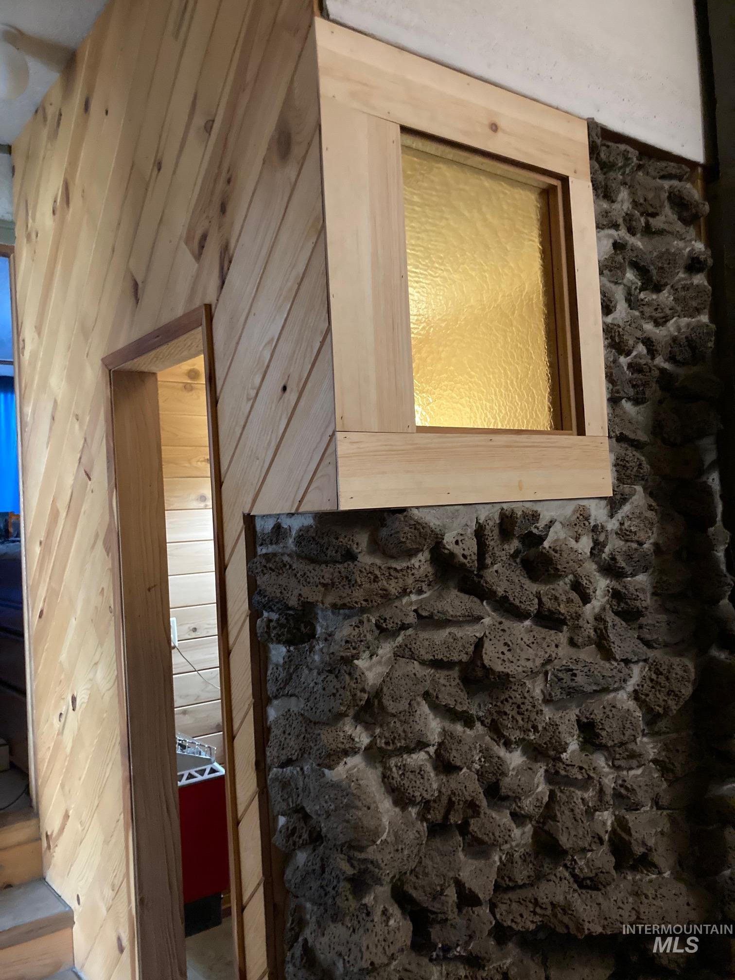 266 Falcon Ridge Road Kooskia, ID 83539 - Photo 26 of 50 Cedar sauna with stone accent wall with a rectangular window featuring textured privacy glass, framed by natural wood trim