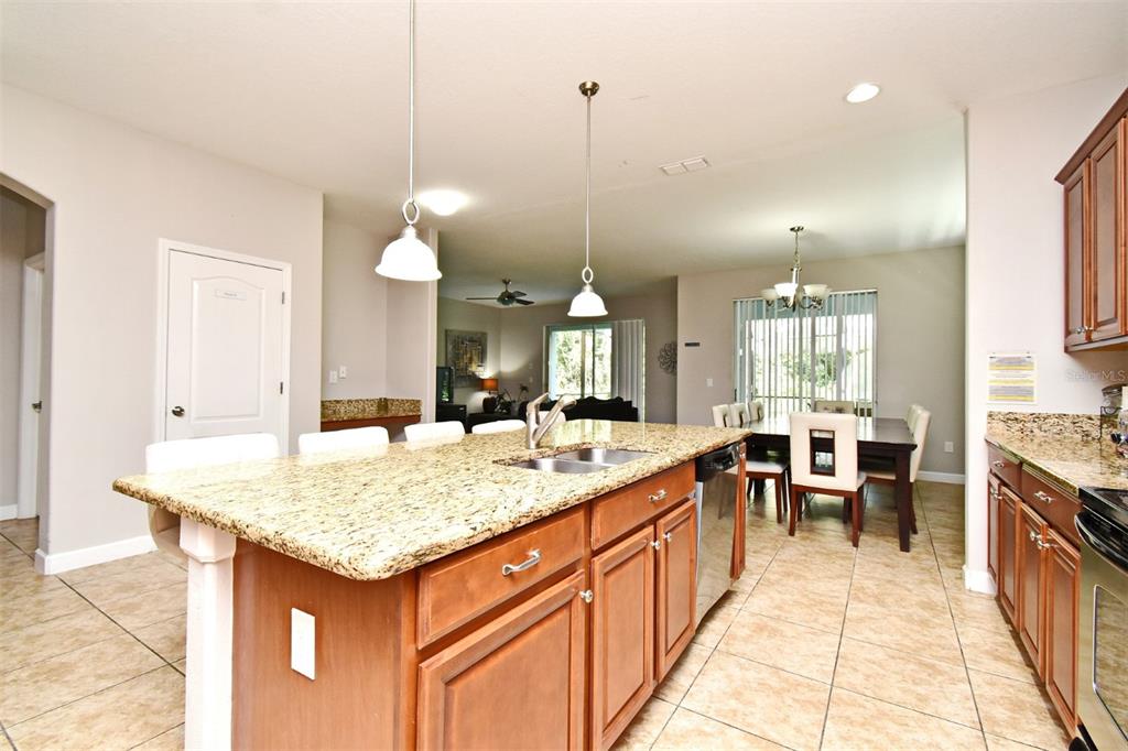 8878 Candy Palm Road Kissimmee, FL 34747 - Photo 11 of 70 a large kitchen with kitchen island a sink stove and a dining table