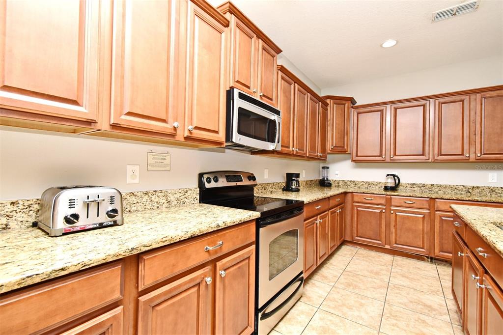8878 Candy Palm Road Kissimmee, FL 34747 - Photo 15 of 70 a kitchen with stainless steel appliances granite countertop a sink and cabinets