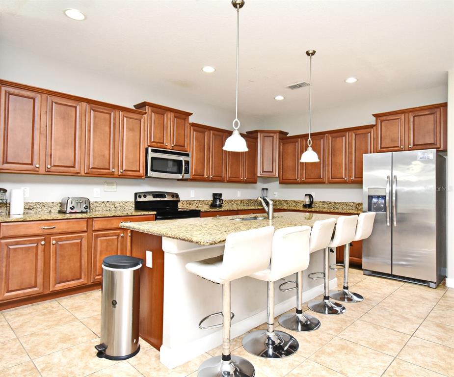 8878 Candy Palm Road Kissimmee, FL 34747 - Photo 17 of 70 a kitchen with stainless steel appliances granite countertop a refrigerator a stove a sink a dining table and chairs with wooden floor
