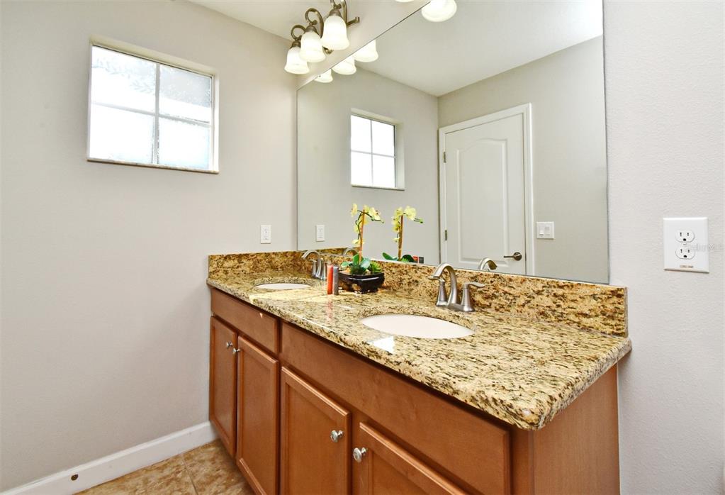 8878 Candy Palm Road Kissimmee, FL 34747 - Photo 32 of 70 a bathroom with a granite countertop sink and a mirror