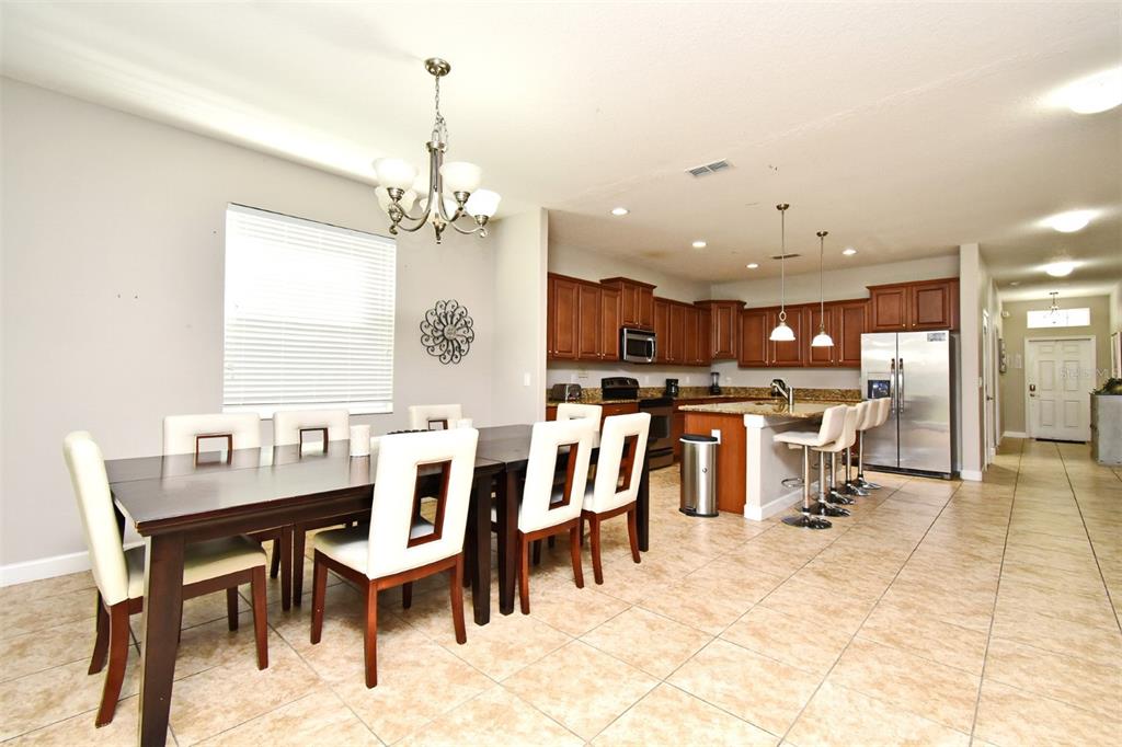 8878 Candy Palm Road Kissimmee, FL 34747 - Photo 9 of 70 a dining room with wooden floor a chandelier a wooden table and chairs