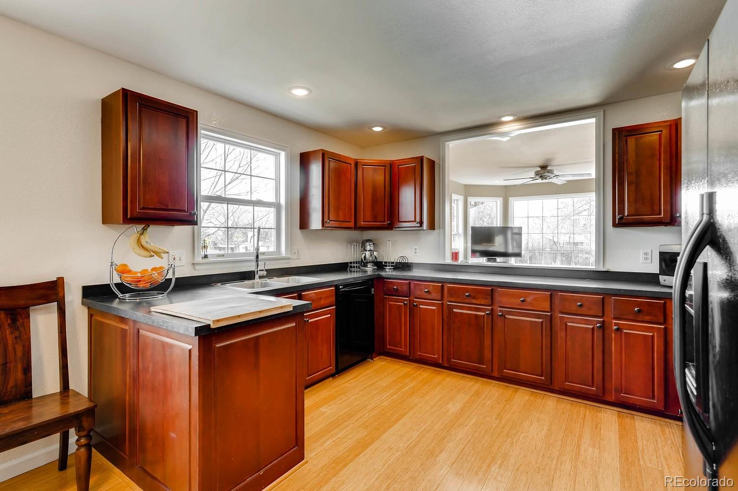 303 West Baseline Road Lafayette, CO 80026 - Photo 7 of 28 a kitchen with stainless steel appliances granite countertop wooden cabinets a sink and dishwasher with wooden floor