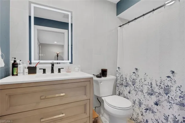 a bathroom with a toilet sink vanity and mirror