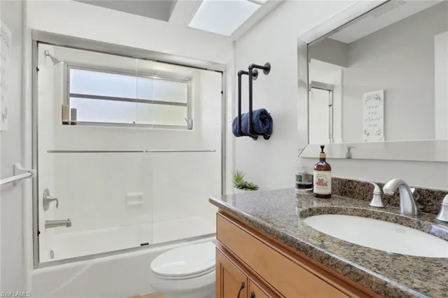 a bathroom with a granite countertop sink a toilet and shower