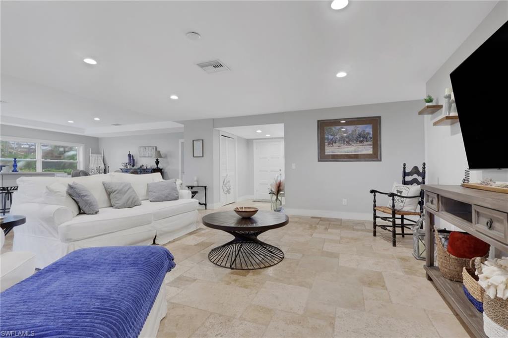 687 Cypress Way East Naples, FL 34110 - Photo 8 of 27 a living room with furniture a flat screen tv and a fireplace