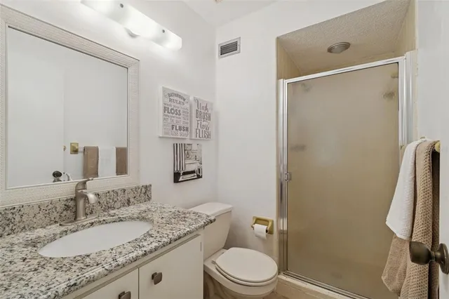 a bathroom with a granite countertop sink toilet and shower