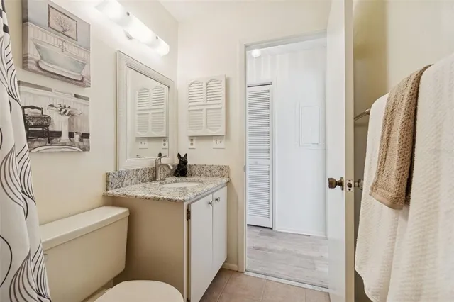 a en suite bathroom with a granite countertop toilet sink and a mirror