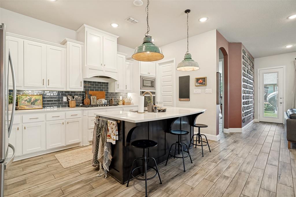 14948 Gentry Drive Aledo, TX 76008 - Photo 11 of 25 Modern kitchen featuring white cabinetry, a dark subway tile backsplash, and a central island