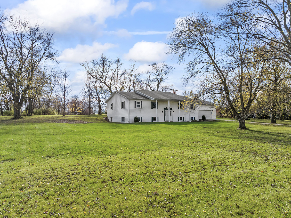 12945 Smith Road Manhattan, IL 60442 - Photo 3 of 43 a view of a white house with a big yard and large trees