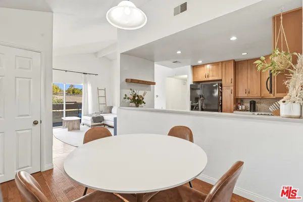 a living room with stainless steel appliances furniture a dining table and kitchen view
