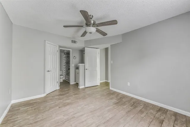a view of empty room with wooden floor and ceiling fan