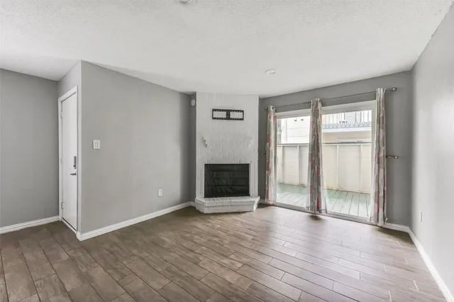 an empty room with wooden floor fireplace and windows