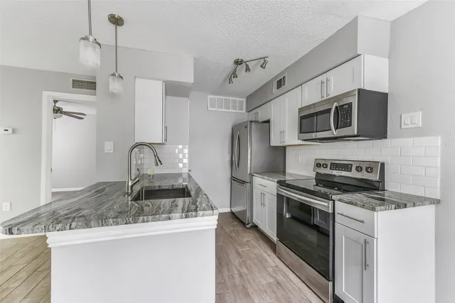 a kitchen with granite countertop a sink and stainless steel appliances