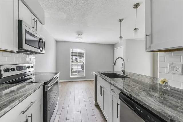 a kitchen with stainless steel appliances granite countertop a sink stove and refrigerator