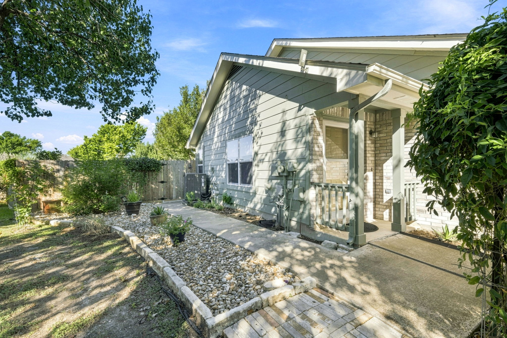 A paved walkway winds along the side of this brick and siding home.