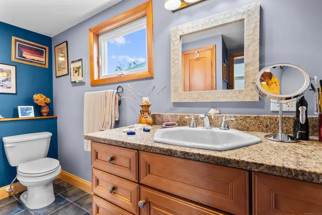 a bathroom with a granite countertop toilet a sink and a mirror