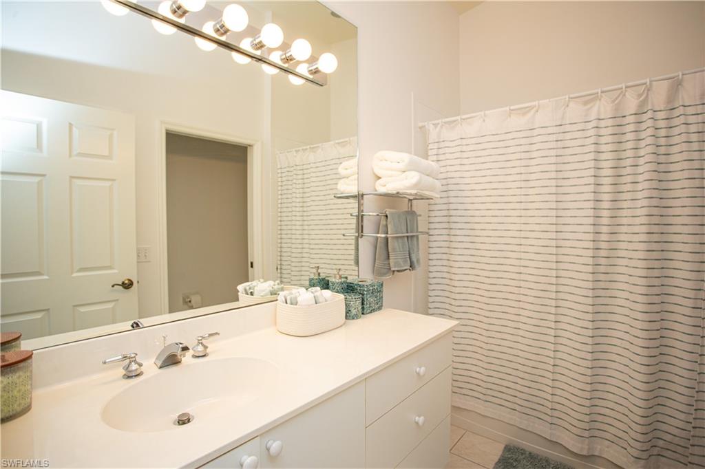 6760 Beach Resort Drive, Unit 2 Naples, FL 34114 - Photo 14 of 24 a bathroom with a sink a mirror and a shower