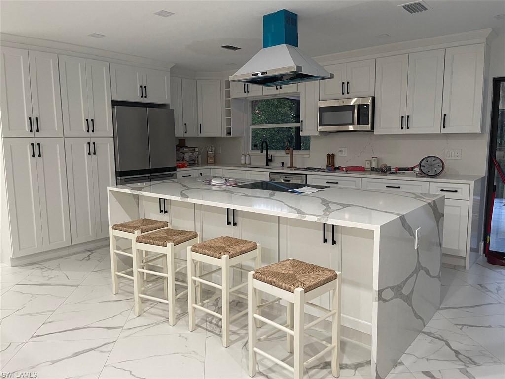 a kitchen with stainless steel appliances a sink a stove a table and chairs