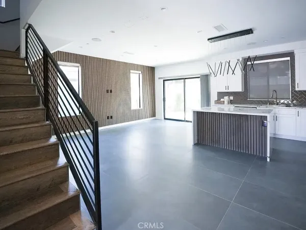 a kitchen with stainless steel appliances granite countertop a stove top oven a sink a refrigerator white cabinets and wooden floor