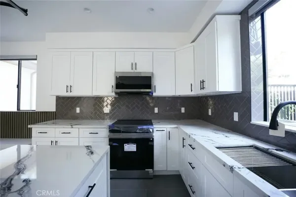 a kitchen with white cabinets and appliances