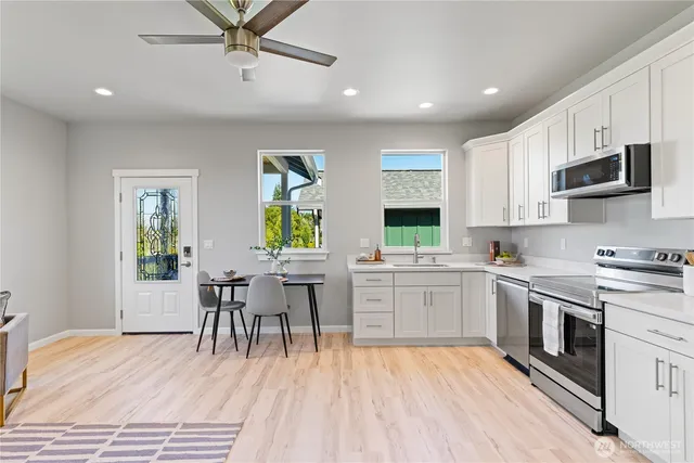 a kitchen with stainless steel appliances a white stove top oven table and chairs