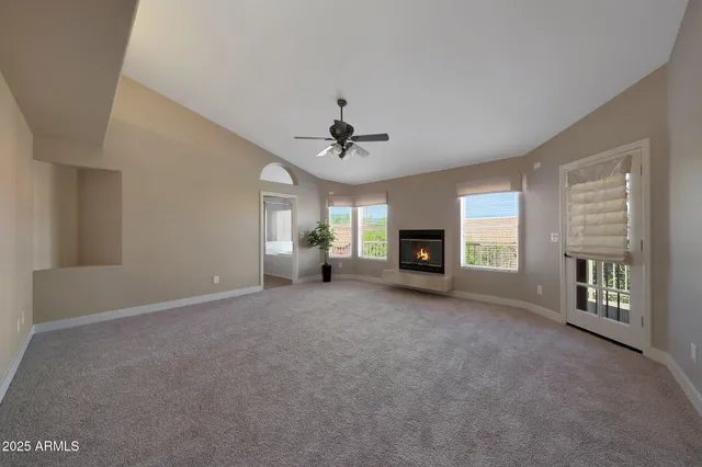 an empty room with windows and ceiling fan