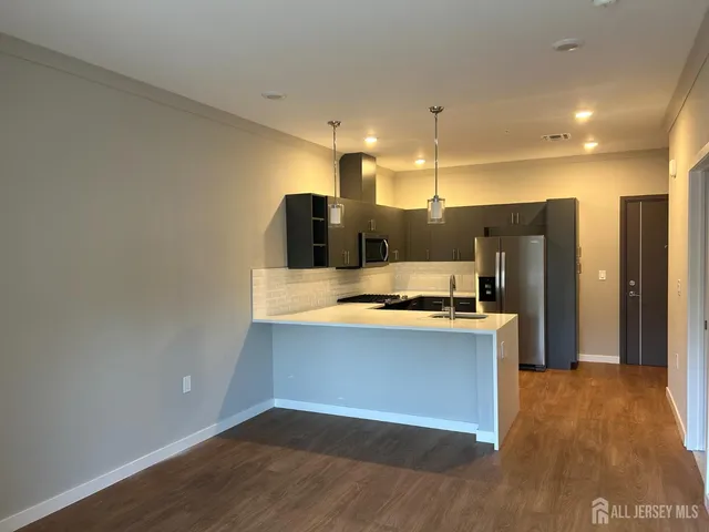 a view of kitchen with stainless steel appliances wooden floor and large window